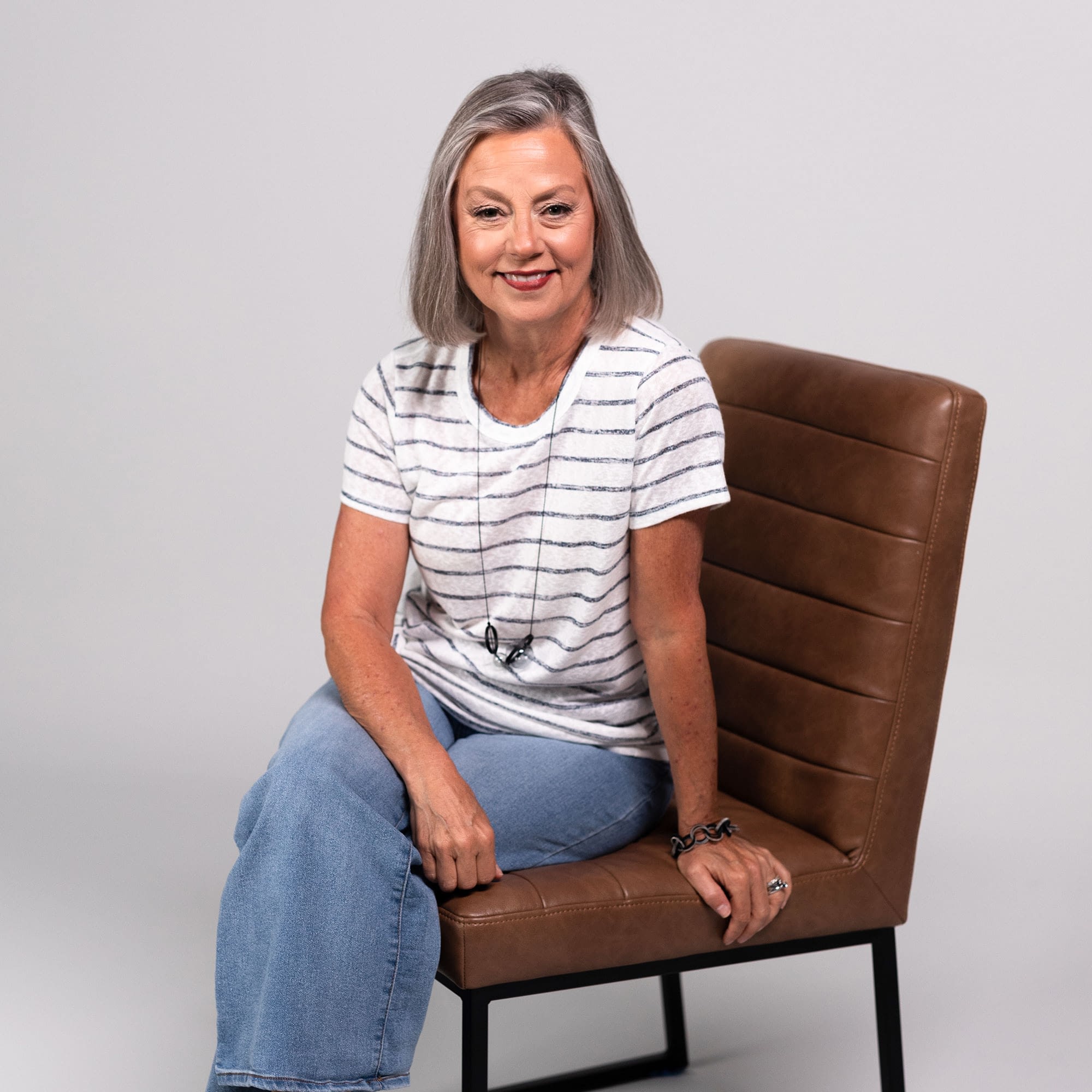 Host Elisa Morgan sitting on brown leather chair smiling