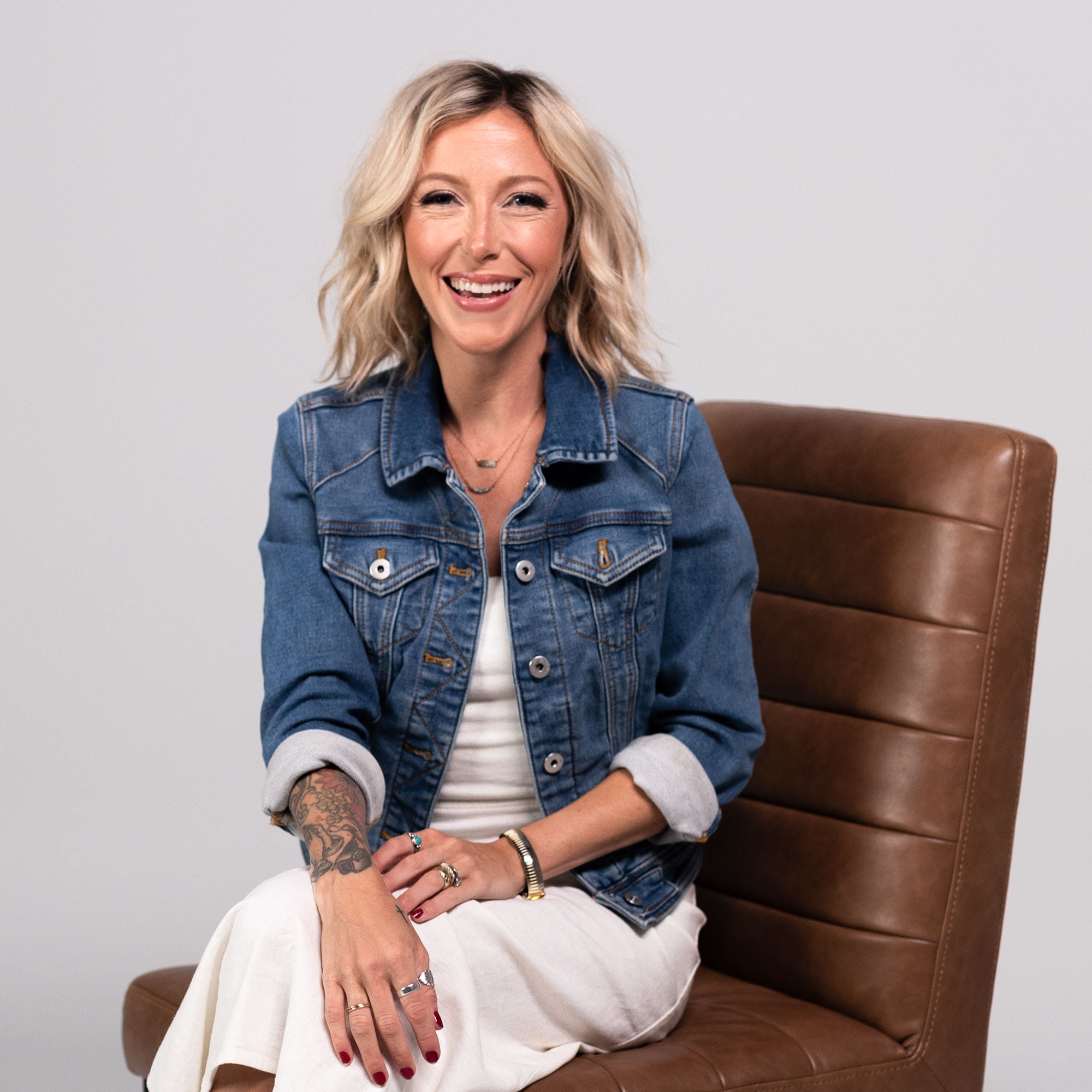 Host Eryn Eddy Adkins in casual attire sitting on brown chair.