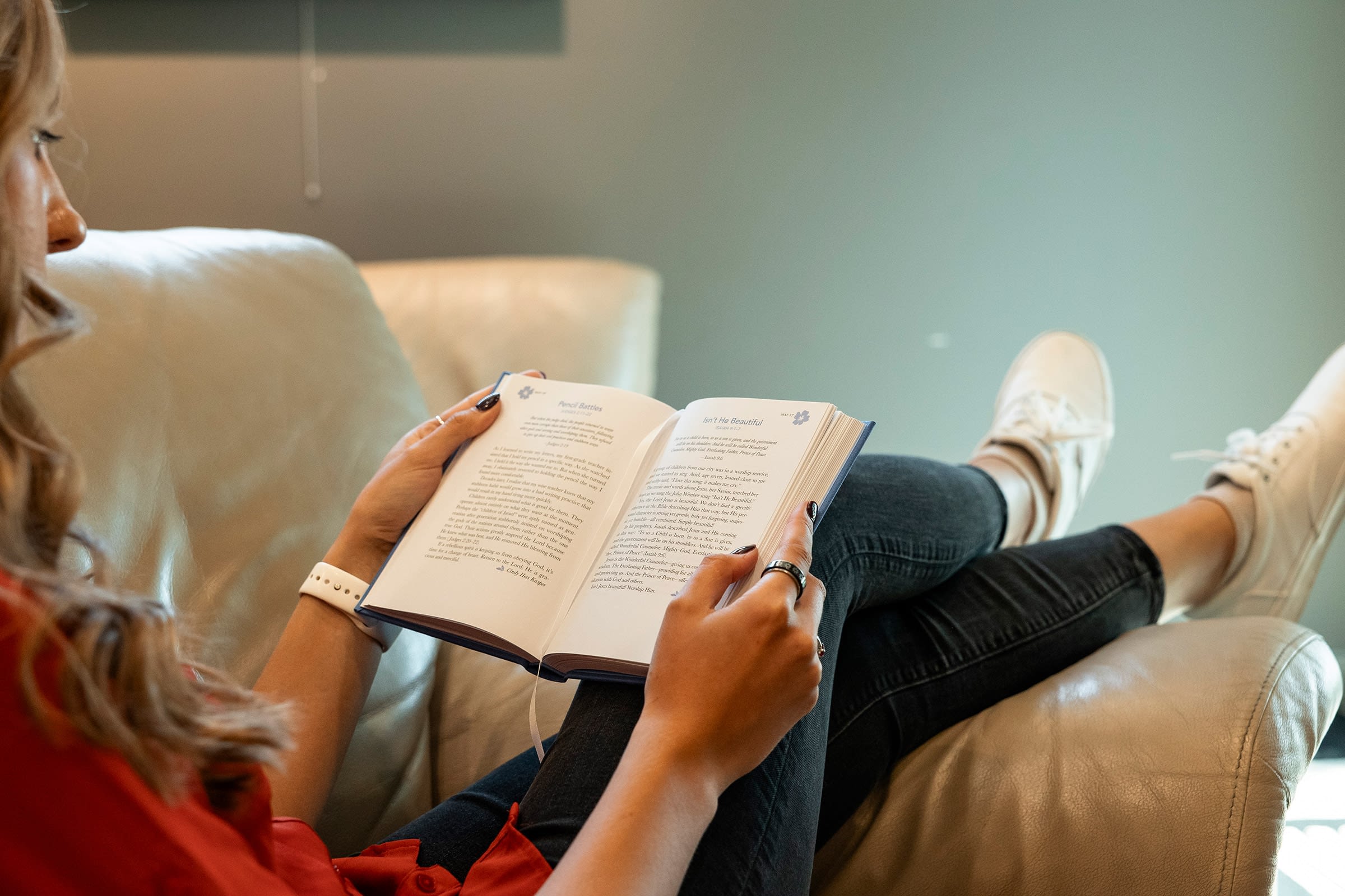 Person reading book on sofa.