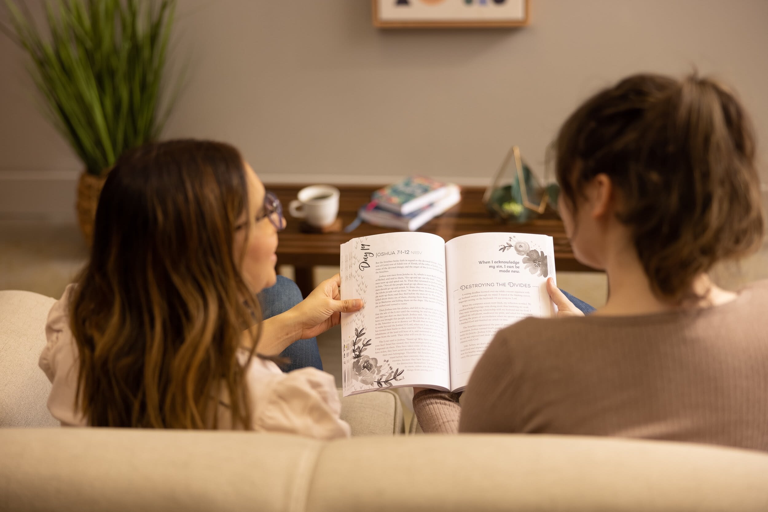 Two women reading a book together.